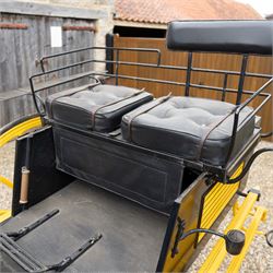 J. W. Thompson Dog Cart

A black and yellow painted two wheeled dog cart with elevated upholstered seat for two, buttoned black leather cushions, high back rail, folding front footboard, louvred sides, side steps, rear drop-down tailboard with chain stays, internal storage compartment, wooden spoked wheels, rubber tyres and shafts for a single horse. The wheel hubs are marked J W Thompson

Dimensions:
Overall length: 366 cm
Width: 160 cm
Height: 190 cm

Wheel Diameter:
Wheels: 139 cm

Seating:
Driver and passenger: 2