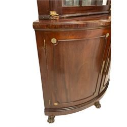 Pair of French Empire design corner cabinets, the straight-front upper section with canted corners and applied half-column pilasters, enclosed by mirror glazed door, the bow-front lower section enclosed by two doors with applied mouldings, mounted by cast metal floral rosettes, skirted base with cast gilt metal hairy paw brass feet