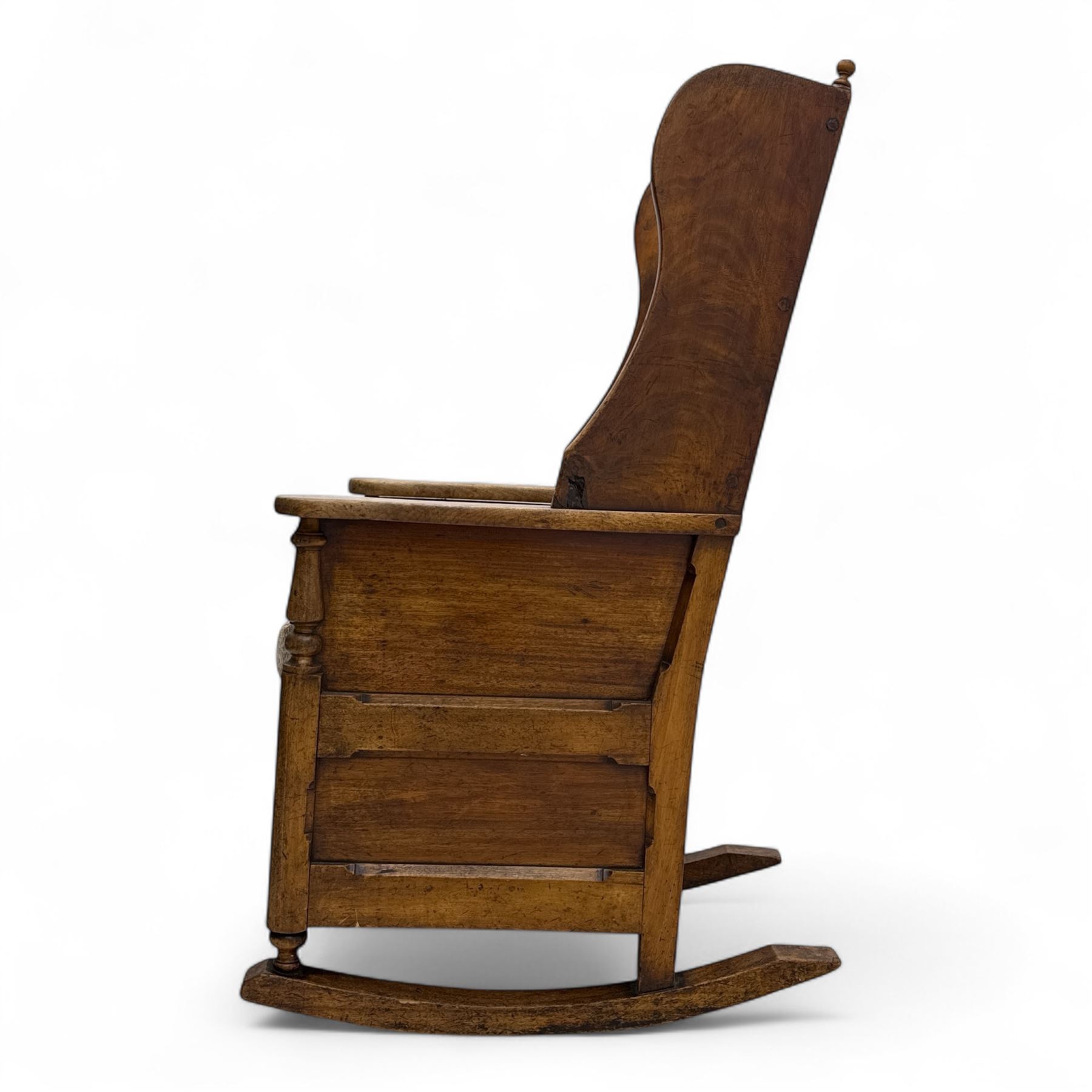 19th-century beech, yew, elm, and mahogany wingback vernacular rocking chair, high back with shaped wings, scroll arms with turned supports, lift-up seat,  square legs on ring turned supports on curved runners 