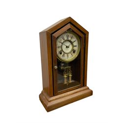 Late 19th century American shelf clock in a mahogany case with a fully glazed door on a stepped plinth, with a card dial with Roman numerals and minute track within a spun brass bezel, 8-day striking movement striking the hours on a bell, with faux mercury pendulum.
