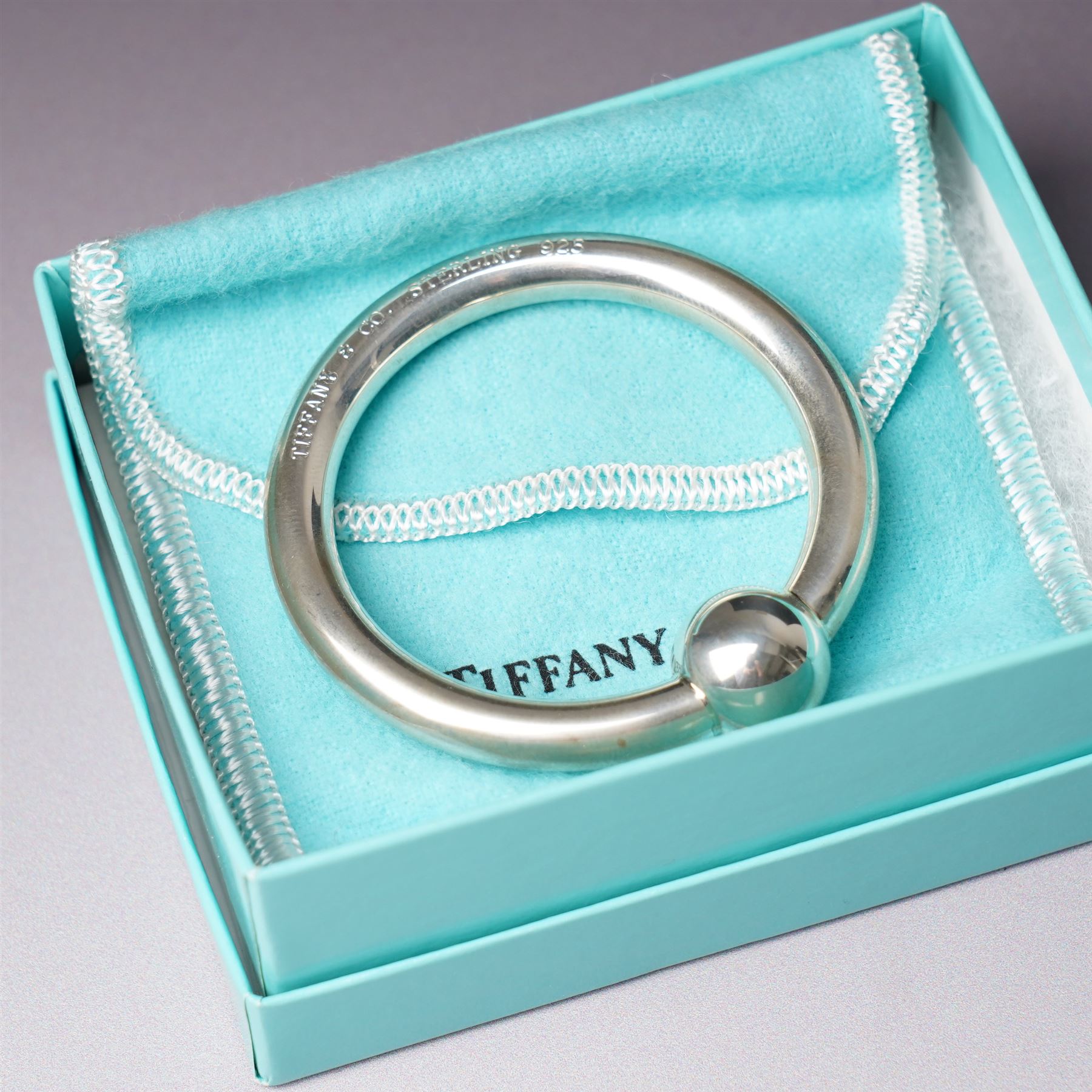 Tiffany silver teething ring marked 'Tiffany sterling 925', boxed, Junghans bedside clock in silver mounted frame, pair of silver sauce ladles and a silver knife