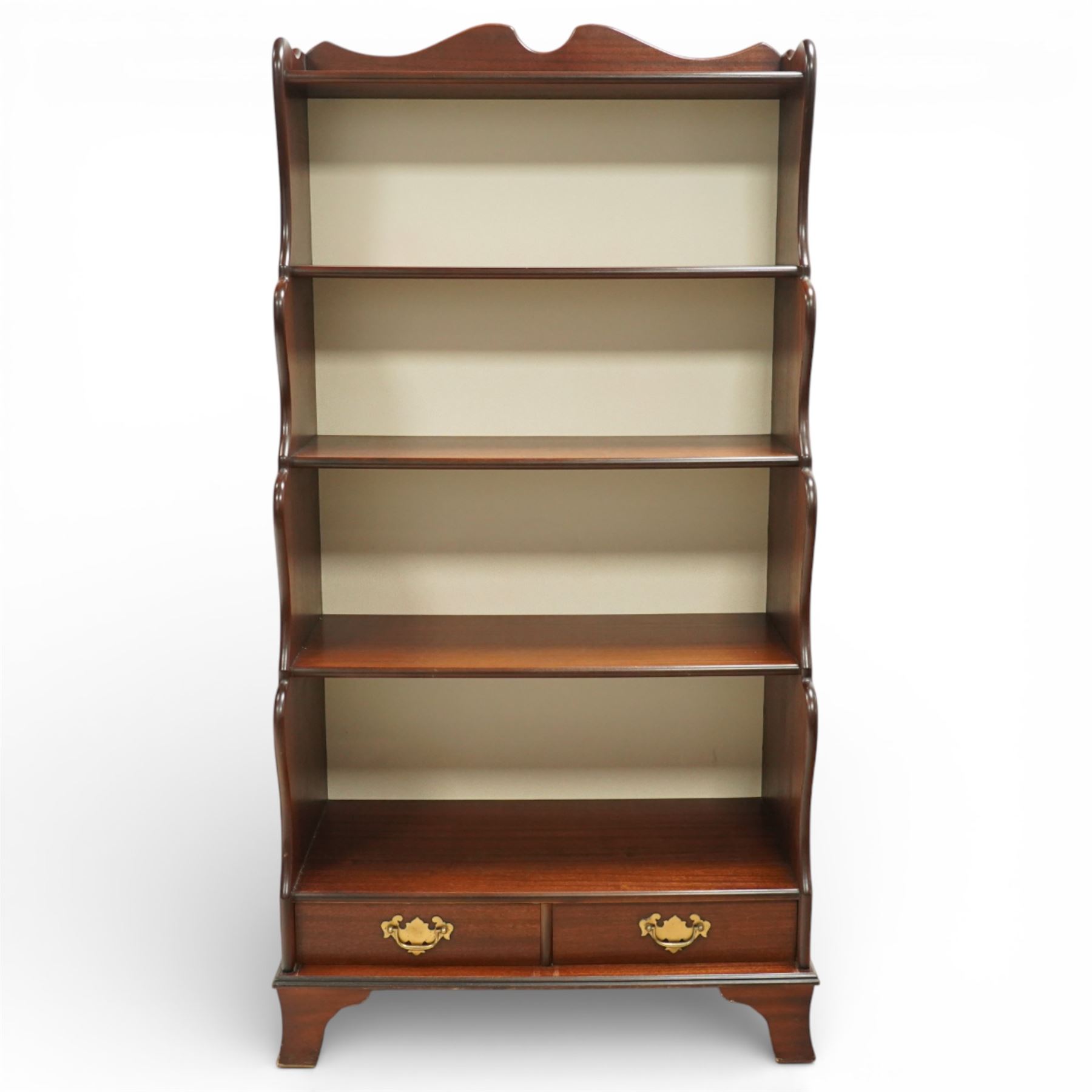 Early 20th century mahogany waterfall bookcase, shaped and serpentine side uprights with scalloped cresting, fitted with four open shelves above two short drawers with brass drop handles, raised on shaped bracket feet