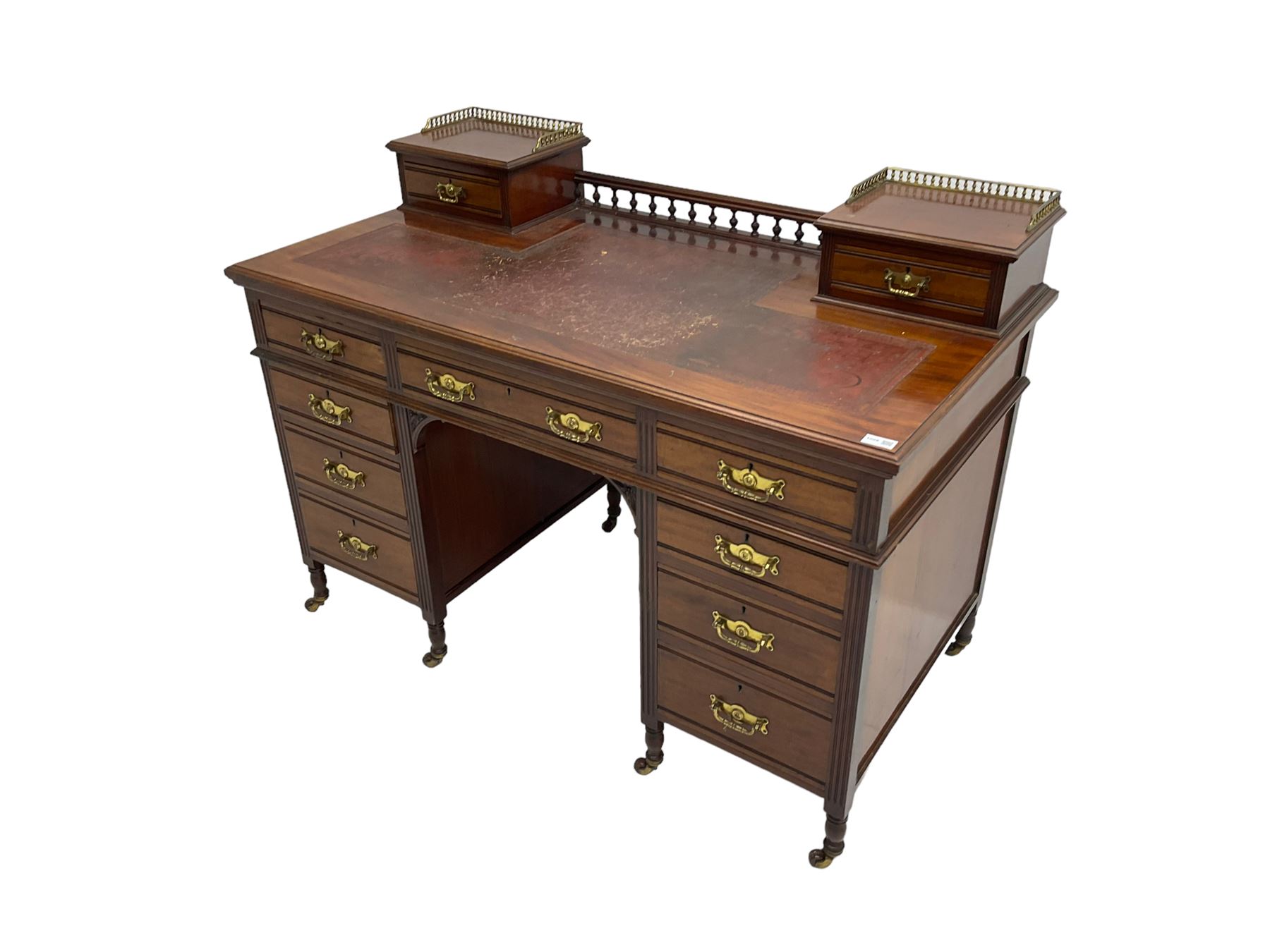 Maple & Co - Edwardian mahogany twin pedestal desk, the raised back with spindle gallery and open shelf to centre flanked by two trinket drawers, rectangular top with inset writing surface, fitted with one long and eight short graduating drawers flanked by fluted uprights, raised on brass and ceramic castors, stamped to central drawer