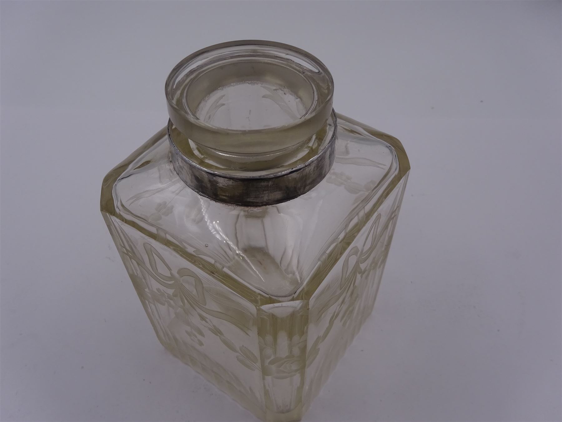 Early 20th century French silver mounted glass scent bottle, the faceted rectangular glass body etched with swags of flowers united by ribbons, with cylindrical silver cover embossed with foliate detail and beaded decoration with gilt interior, marked with Minerva's head, with white metal collar and glass stopper, H17cm