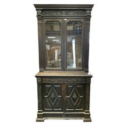 19th century continental carved oak bookcase on cupboard, projecting cornice above two glazed doors enclosing adjustable shelving, base unit complete with frieze drawer above two panelled cupboards, raised on stile supports 