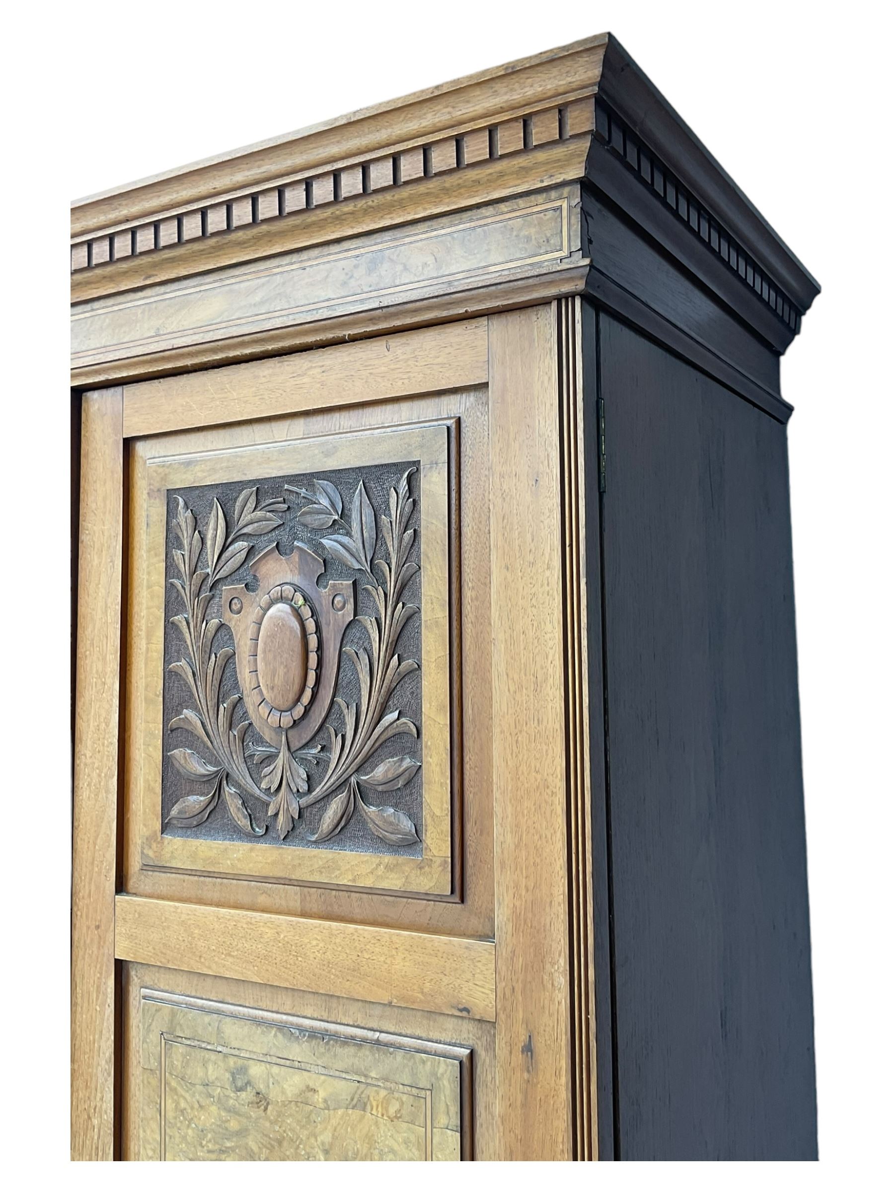 Late Victorian walnut triple combination wardrobe, projecting moulded and dentil cornice, central shaped bevelled mirror glazed door, cartouche and curled leaf carved panels over figured walnut veneered panels, fitted with drawer to base, on bracket feet
