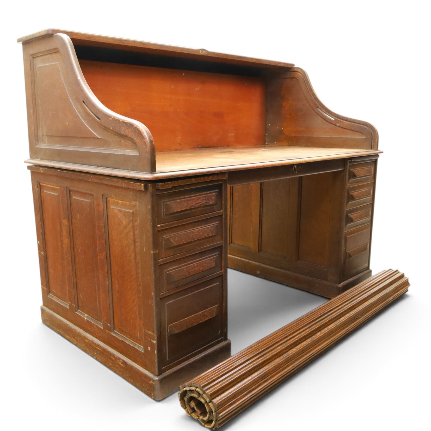 Cutler - Late Victorian oak pedestal tambour desk, the tambour shutter enclosing fitted interior, pull-out writing surface over central kneehole flanked by two pedestals each fitted with four drawers with moulded fronts, pull-out slides above, panelled sides, on moulded plinth base