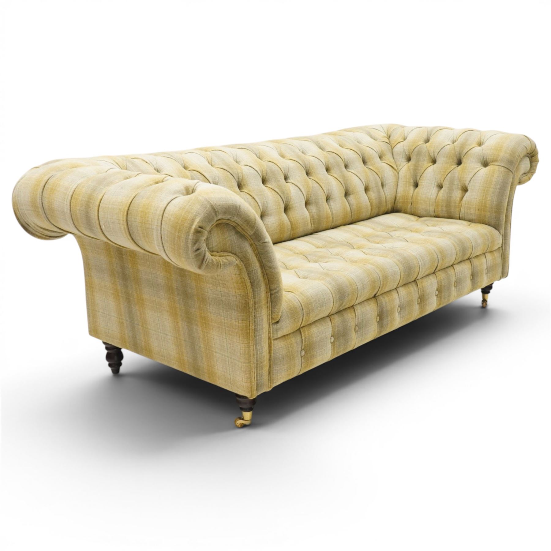 Late 20th century Chesterfield style two seat sofa, upholstered in muted green and yellow tartan fabric with buttoned back, arms and seat, on turned front supports with brass castors