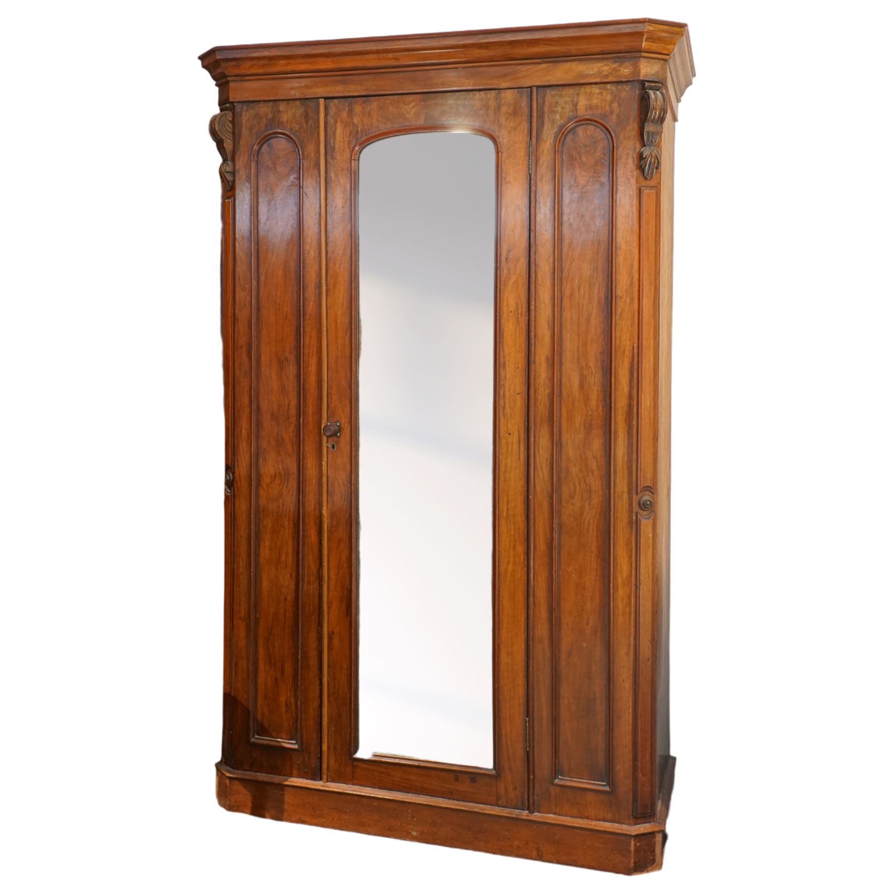 Victorian late 19th-century mahogany wardrobe, moulded cornice with rounded corners above arched mirror door, flanked by arched panels and side with carved corbels, on plinth base  