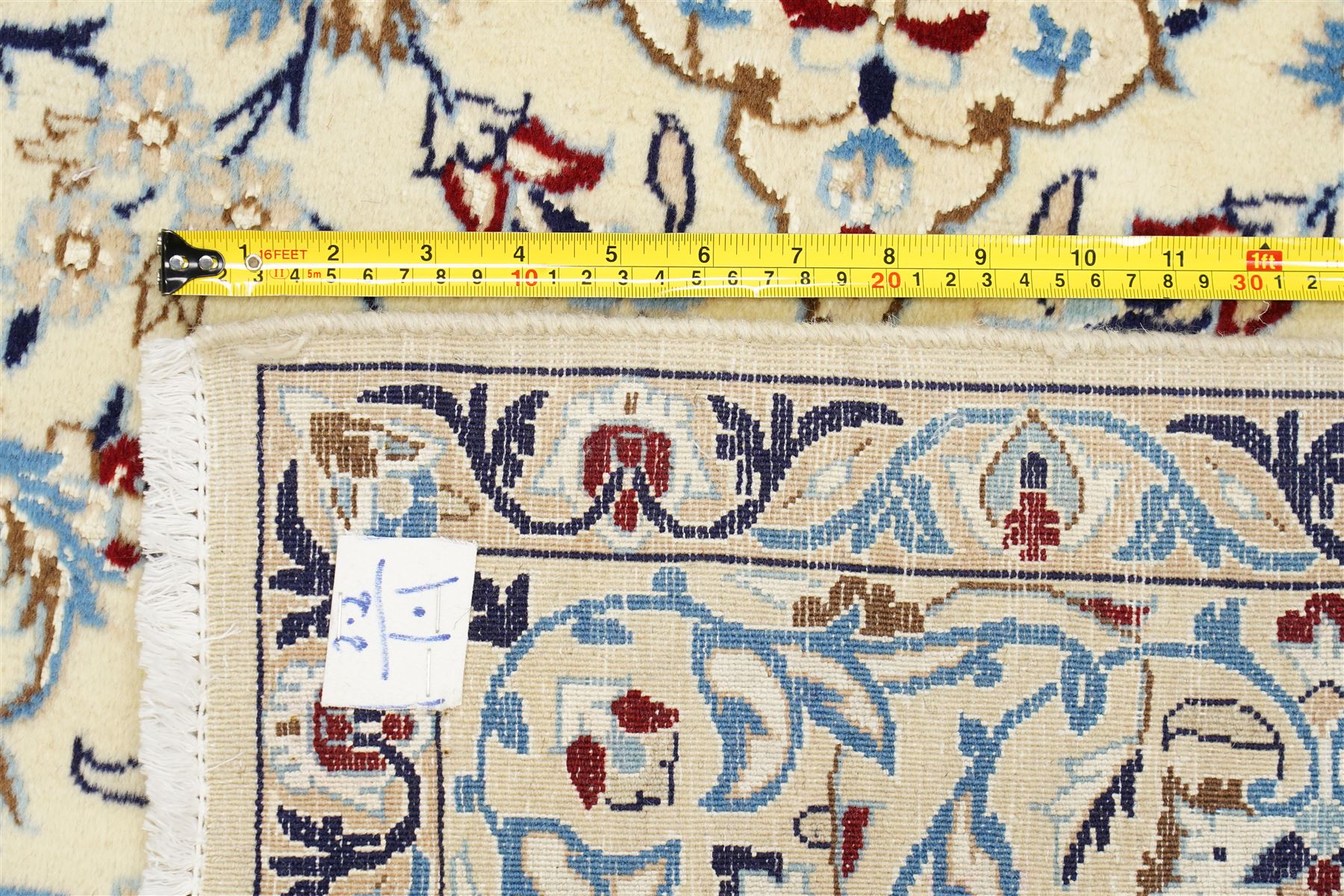 Central Persian Nain hand-knotted rug, ivory field with central medallion in tones of indigo and blue, issuing vinery, palmettes and floral sprays with conforming spandrels, dark blue main border of floral vinery and stylized palmettes, framed by multiple guard borders, with cotton fringe ends 