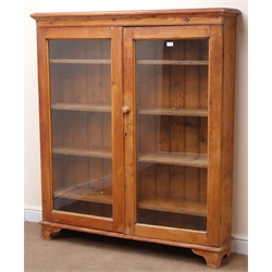  Early 20th century pitch pine bookcase, two glazed doors enclosing four shelves, bracket supports, W133cm, H155cm, D30cm  