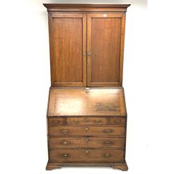 Georgian oak bureau bookcase, projecting cornice, two doors above single fall front enclosing fitted interior above three short and three long graduating drawers, ogee bracket supports 