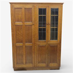 Edwardian oak glazed cabinet, moulded cornice above a panelled front and sides, fitted with lead glazed doors enclosing shelved interior, left side full length cupboard converted to enclose a gun cabinet, on a plain plinth base 