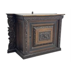 18th century and later carved oak cupboard, enclosed by panelled door carved with central bird motif and scrolled leafage with an outer ebony band, the frieze and uprights carved with repeating lunette and floral designs, flanked by scrolled foliate carved upright brackets