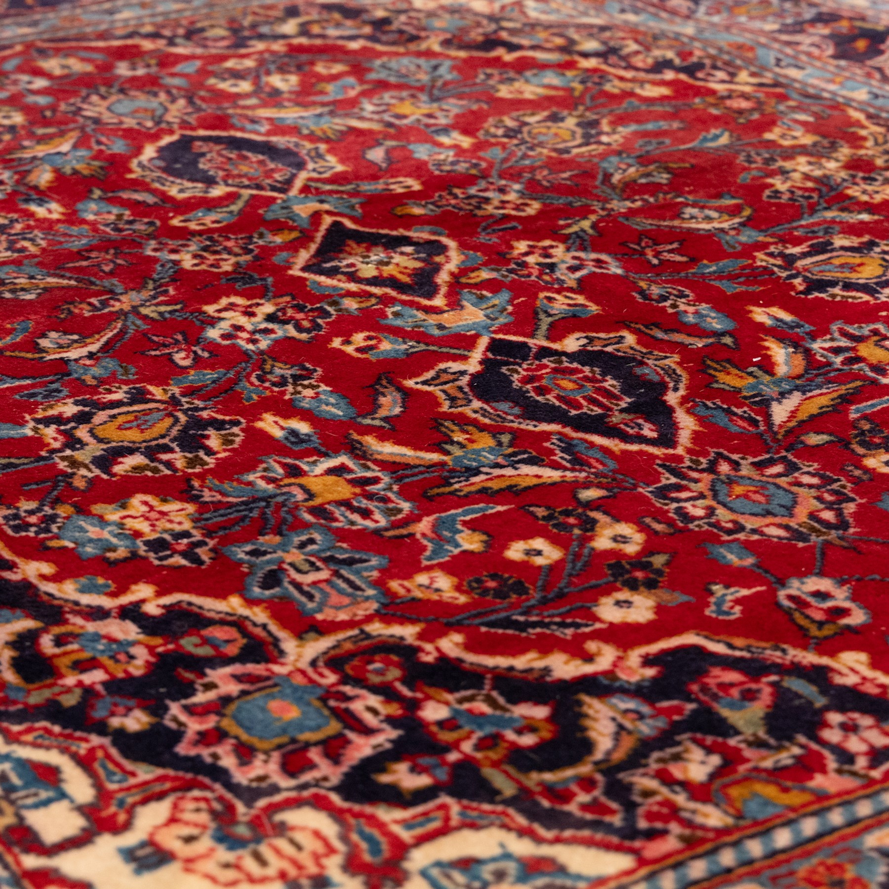 Two Persian rugs, the larger with a crimson field decorated with three linked indigo medallions amongst flowering tendrils, shaped floral spandrels and an indigo palmette border, (161cm x 129cm), the smaller with a crimson field centred by an ivory rosette amongst stylised flowering plants, within a dark floral border, (114cm x 79cm) (2)