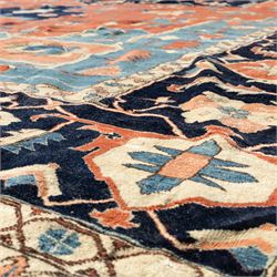 Exceptionally large Northwestern Persian Heriz, hand-knotted carpet, madder red field with a bold stepped medallion in indigo and ivory, and light blue spandrels within a dark indigo border of rosettes and angular vine motifs 




