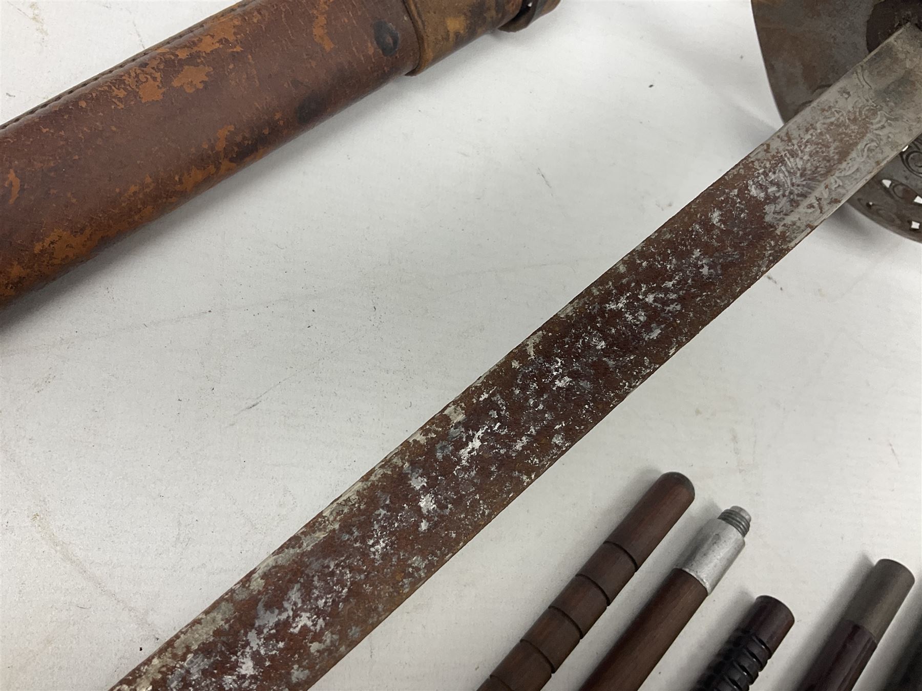 George V 1897 pattern Infantry officers sword, the 82cm single fullered blade with traces of etched detail and George V crown cipher, the ricasso marked Hawksworth Sheffield, pierced half basket hilt with George V cypher, wire-bound fish-skin grip with brass pommel and backstrap; in leather scabbard L102cm overall; together with two sectional gun cleaning rods; swagger stick made of leather strips etc