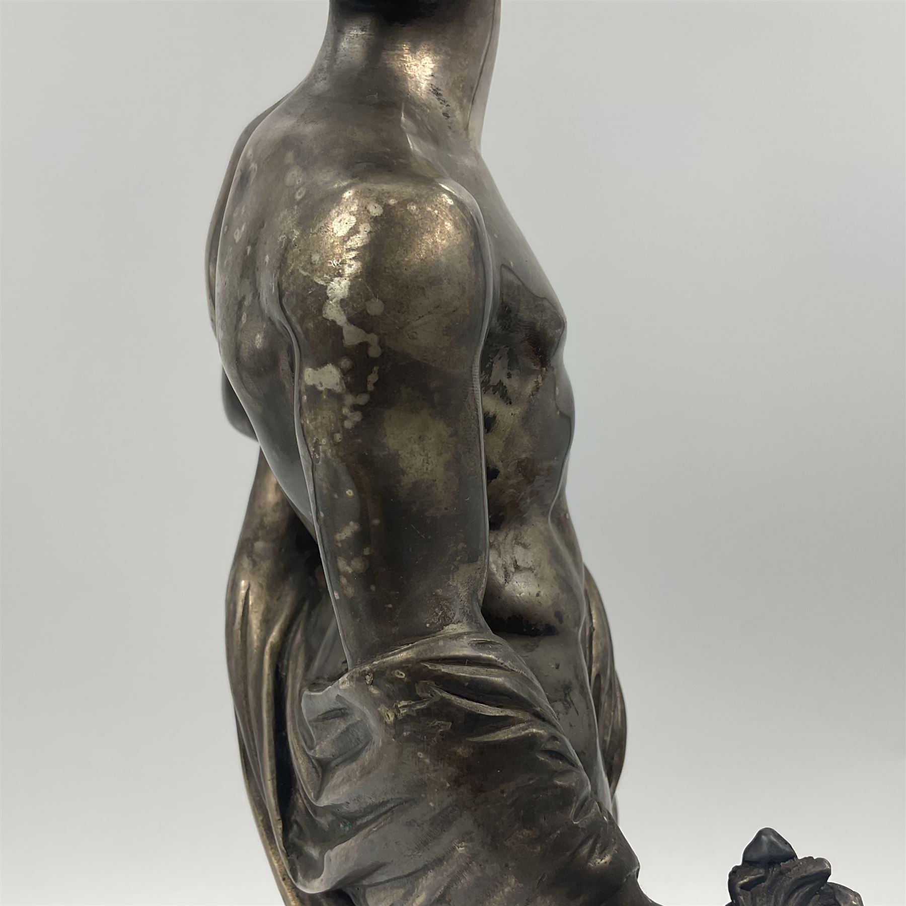 20th century silver plated figure, modelled as a classical male figure, possibly Prometheus, holding flames, one foot resting atop a small dragon, upon a circular spreading base, overall H37.5cm