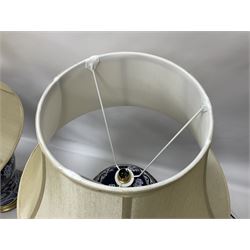 Pair of blue and white table lamps, each of baluster form, decorated with prunus blossom, within stylised borders, raised upon circular gilt base, excluding fittings H48cm