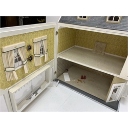 A large dolls house, with shop front ground floor, and wall papered interior with curtains and fireplaces, H94cm L67cm D43.5cm.  