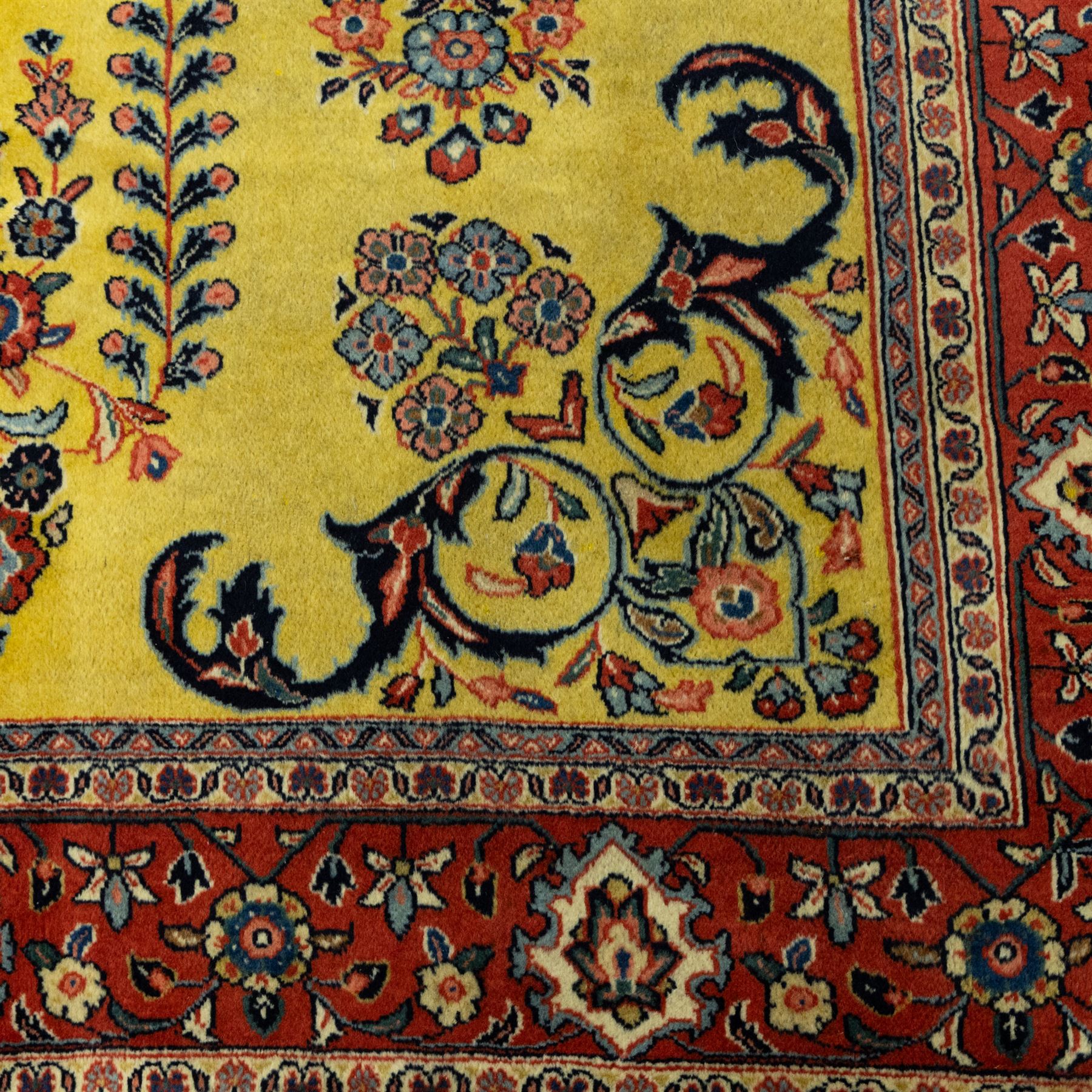 Persian Sarough hand-knotted carpet, golden yellow ground, with an all-over floral design centred by a small floral motif, the field decorated with mirrored flowering sprays, scrolling vines and dark navy foliate corner motifs, enclosed by a terracotta border with repeating flowerheads and palmettes, flanked by narrow guard stripes, with cotton fringes