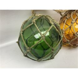 Two glass fishing floats, including green and orange example, both within rope netting, largest D13cm
