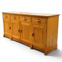 Acorn Industries - oak dresser base or sideboard, the rectangular top over three drawers with protruding oak handles, over four panelled cupboard doors enclosing a single shelf, raised on stepped feet, carved with acorn signature, by Alan Grainger, Brandsby