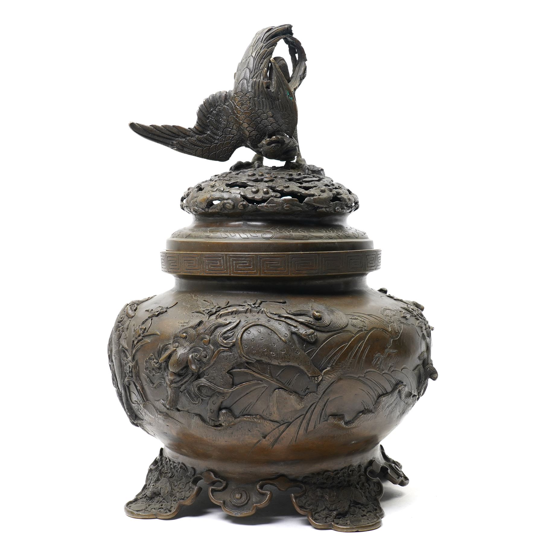 Japanese Meiji period bronze Koro, c.1870-1880, of squat baluster form, each foot with elaborate floral and mythical creature decoration, the body depicting two lions in chase, the rim with Greek key border, the pierced cover with eagle finial, Yoshida foundry mark to base, H50cm