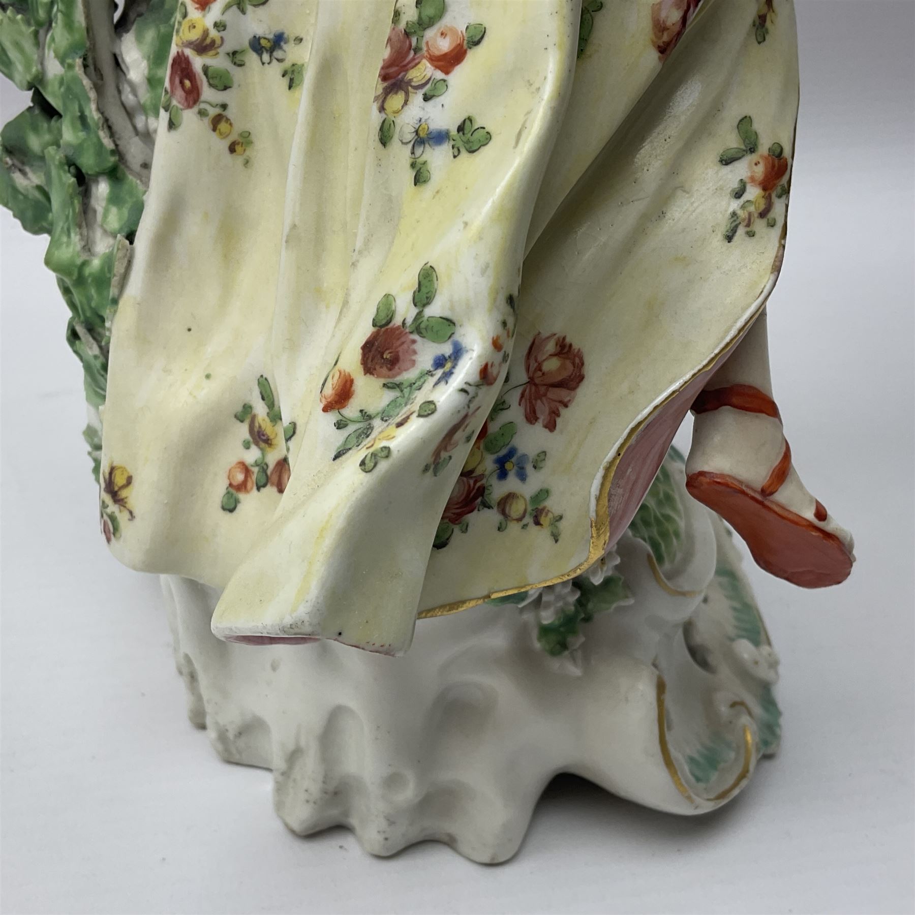 18th century Derby figure of Diana the huntress, circa 1760, modelled reaching for an arrow from quiver across her back, with recumbent hound at her feet, upon a scrolled base with bocage detail, H27.5cm