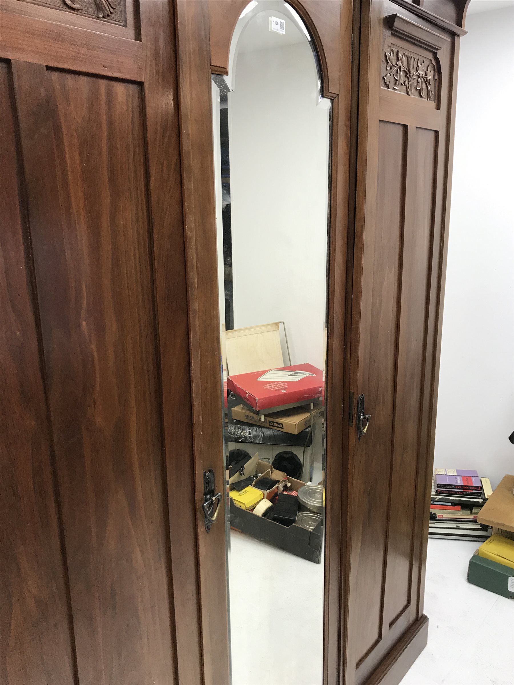 Irish Arts & Crafts walnut triple wardrobe circa 1908, projecting cornice above three doors enclosing fitted interior, single full length bevel edge mirror, platform base, W173cm, H204cm, D56cm