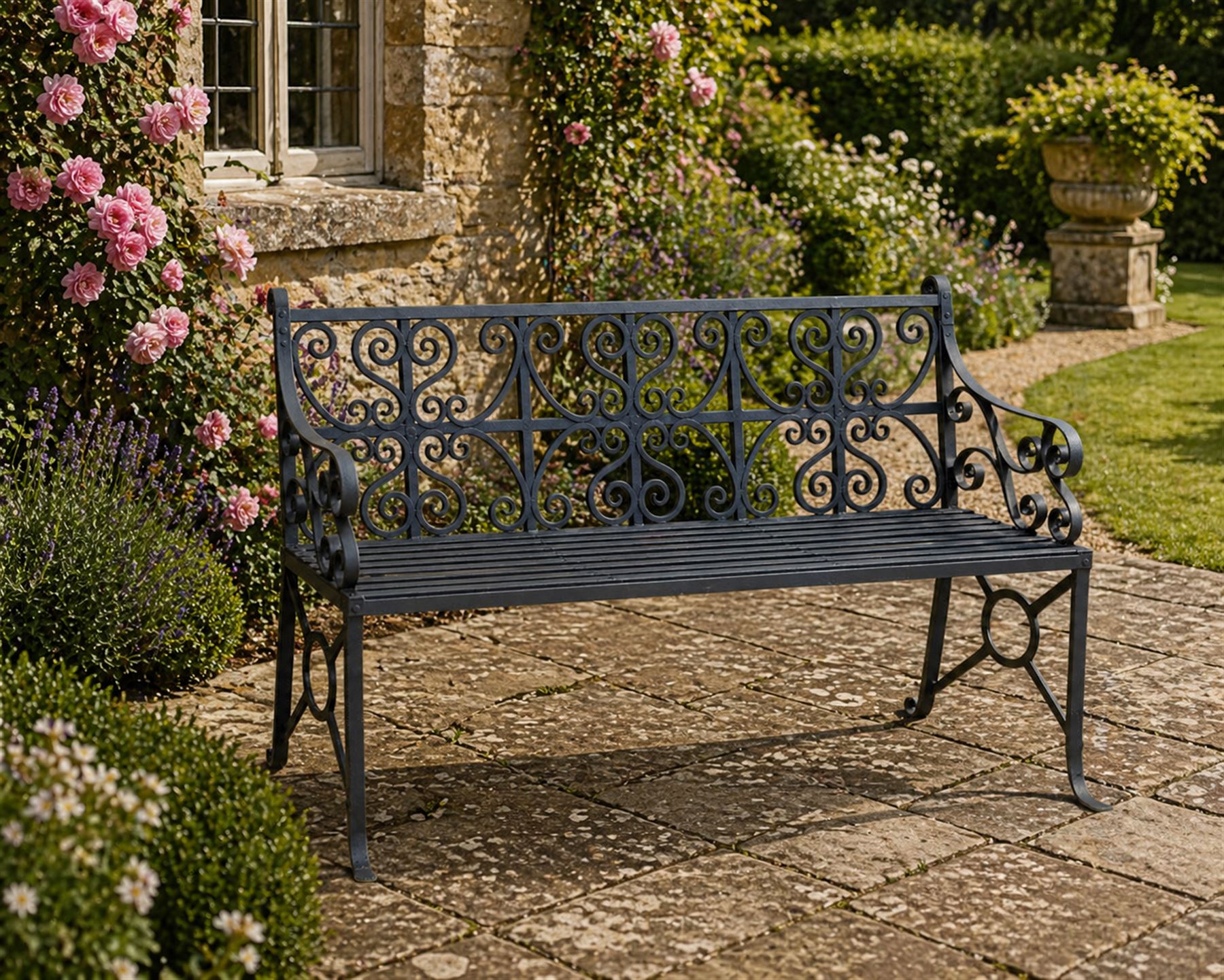 Regency period wrought iron garden bench, hand forged in wrought iron and finished in matt black paint, decorated with intricate scrollwork and featuring circular geometric ends, strapwork seat