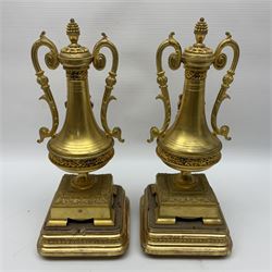 Pair of gilt metal urns, with twin handles, applied cherub detail and stylised pineapple finials, each upon a stepped gilt base, H28cm  