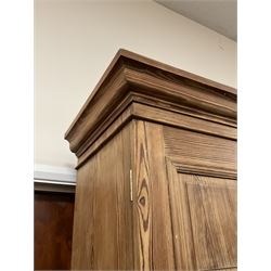 Victorian pitch pine double wardrobe, projecting moulded cornice over two panelled doors, the interior fitted with hanging rail and hooks, single drawer to base