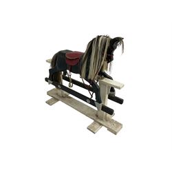 20th century black painted rocking horse on white painted trestle base, fitted with saddle and stirrups 