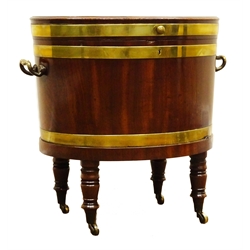  Regency mahogany brass bound oval wine cooler, hinged lid enclosing lead lined interior, brass side carry handles, the ring turned supports with brass sockets and castors, W62cm, H58cm, D43cm  