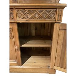 Ecclesiastical Gothic design waxed pine dresser, projecting cornice over four glazed doors, pierced and carved tracery work, moulded rectangular top over four drawers and four cupboards, the doors with Gothic design arched panels carved with flower heads and foliage, on plinth base