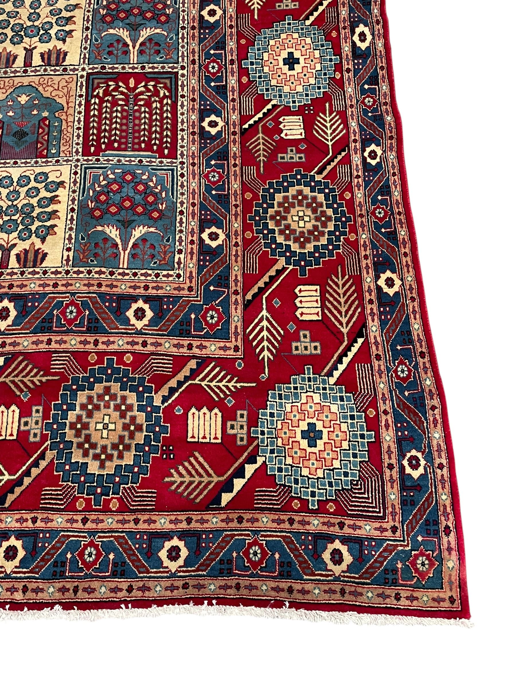 Persian Bakhtiari crimson ground carpet, the field divided into seventy panels decorated tree of life motifs, mihrabs and stylised plants, the border decorated with repeating circular medallions formed of Hac motifs, floral pattern guard stripes 