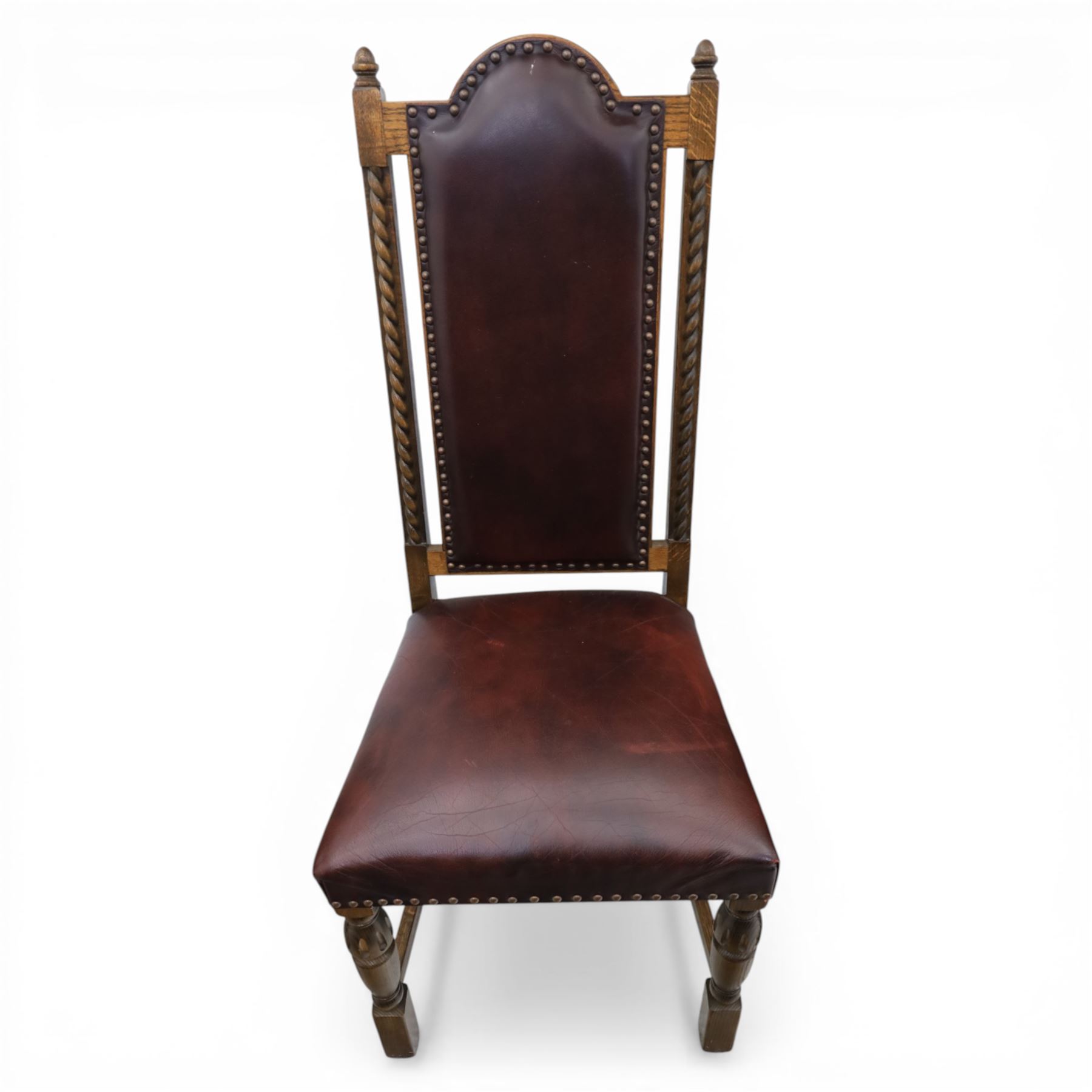 Carolean revival oak dining table and eight chairs (7+1), refectory table with rectangular boarded top and cleated ends, raised on shaped trestle end supports with central stretcher, accompanied by eight high-back chairs including a carver, leather upholstered panels and seats with studwork, on turned legs with stretchers.