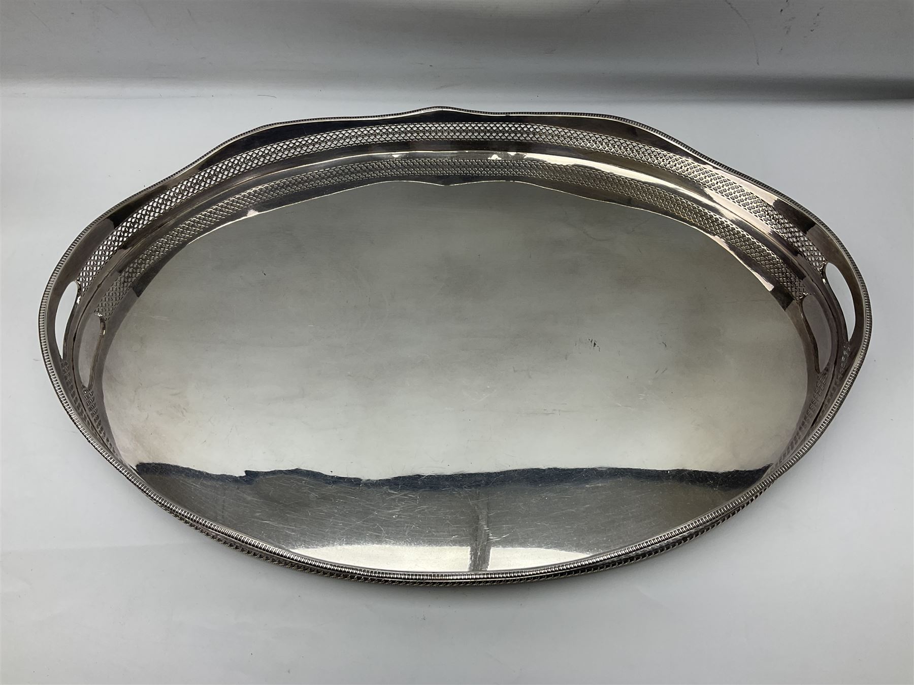 Pair of Mappin and Webb silver plate pierced pedestal bon bon dishes, together with other silver plate comprising teapot stand engraved with lion's head to centre, two cut glass claret jugs, two bottle coasters with acorn decoration, two open salts upon dolphin mounts, tea caddy, three piece cruet set and a large oval tray with pierced sides and upon four ball feet