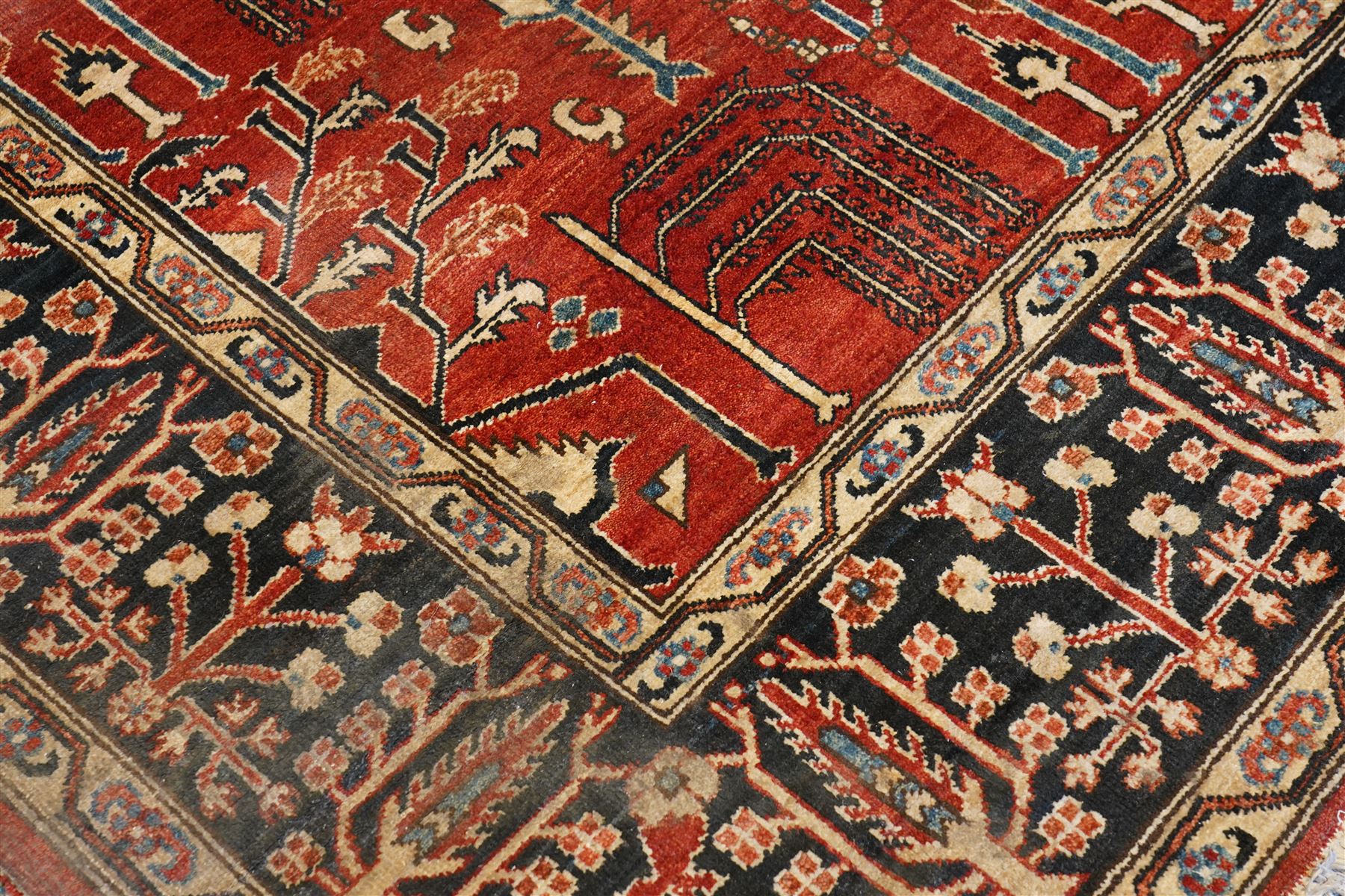 Anatolian crimson ground tribal rug, the field decorated with repeating geometric tree of life motifs with figural designs, the indigo guard band with stylised palmettes