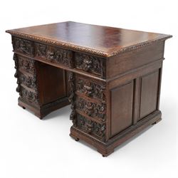 Victorian carved oak twin pedestal desk, moulded and foliate carved rectangular top with leather inset, fitted with nine drawers, each carved with scrolling foliage and lion mask handles, on skirted base 