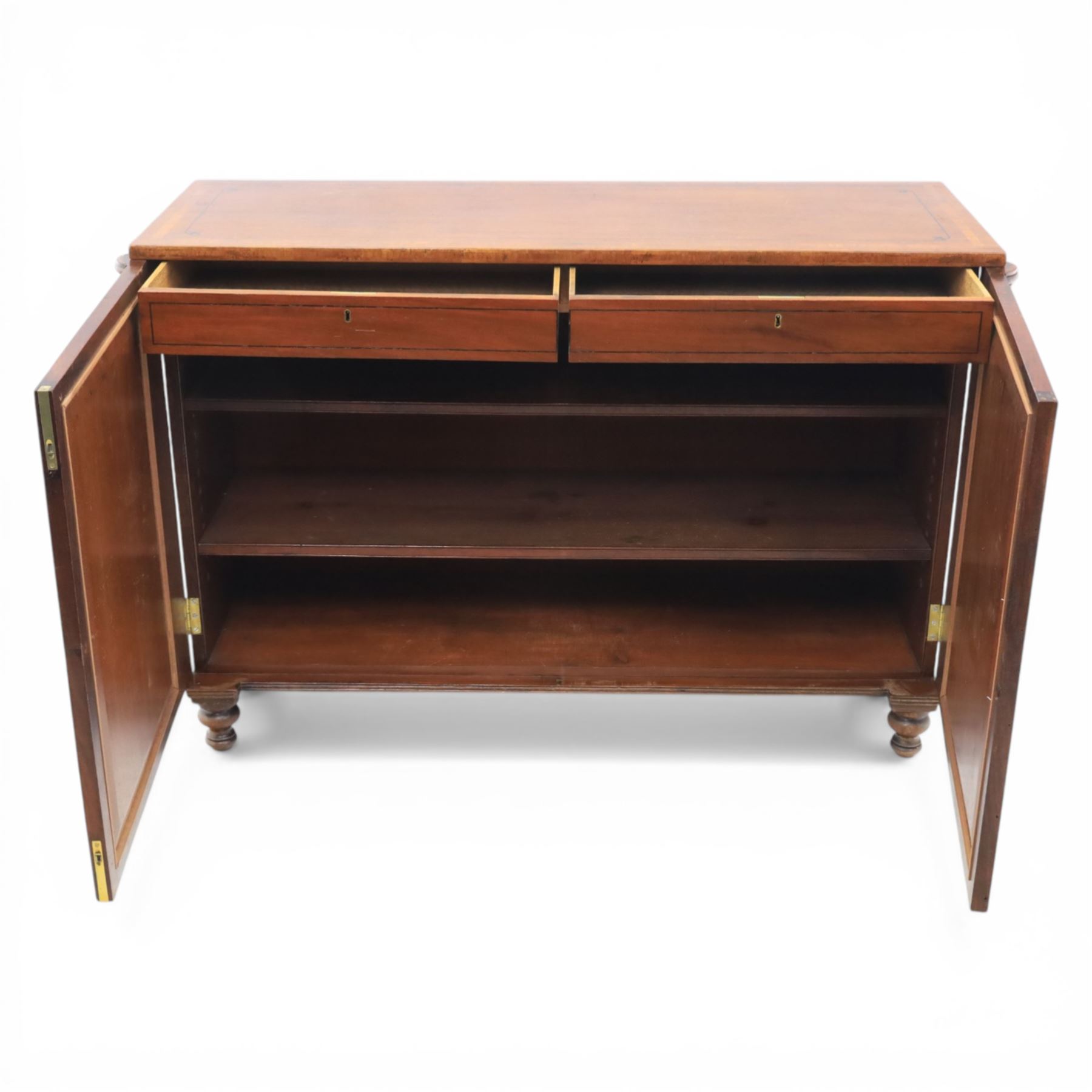 Late 20th century Regency style mahogany side cabinet, the rectangular crossbanded top with ebonised line inlay, above a pair of brass lattice grille doors with pale green fabric backing enclosing a shelved interior and two frieze drawers, flanked by reeded corner pilasters, upon turned tapering feet