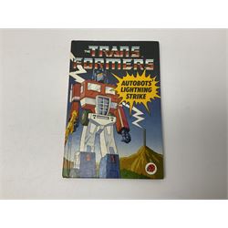Four 1980sTransformer G1 - Optimus Prime 1984; DinoBot Sludge (Diplodocus) 1984; Cyclonus 1986; and Runamuck 1986; with paperwork; seven Bandai Robo Machines Robots/Transformers; almost fully stocked Panini Sticker album; two annuals; three comics; two posters; and Ladybird story book