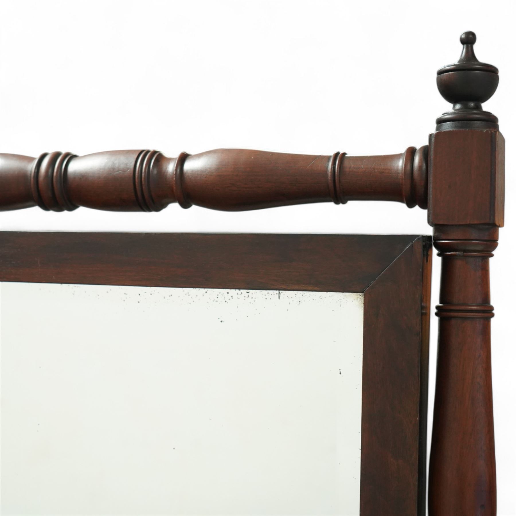 Late 19th-century Regency-style mahogany cheval mirror, rectangular mirror plate within turned uprights and turned cross stretchers supported on down-swept legs terminating in brass paw castors 