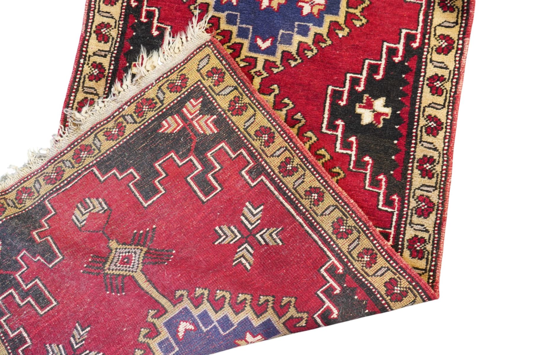 Turkish crimson ground rug, the field decorated with four hooked lozenges, trailing border with stylised flower heads 