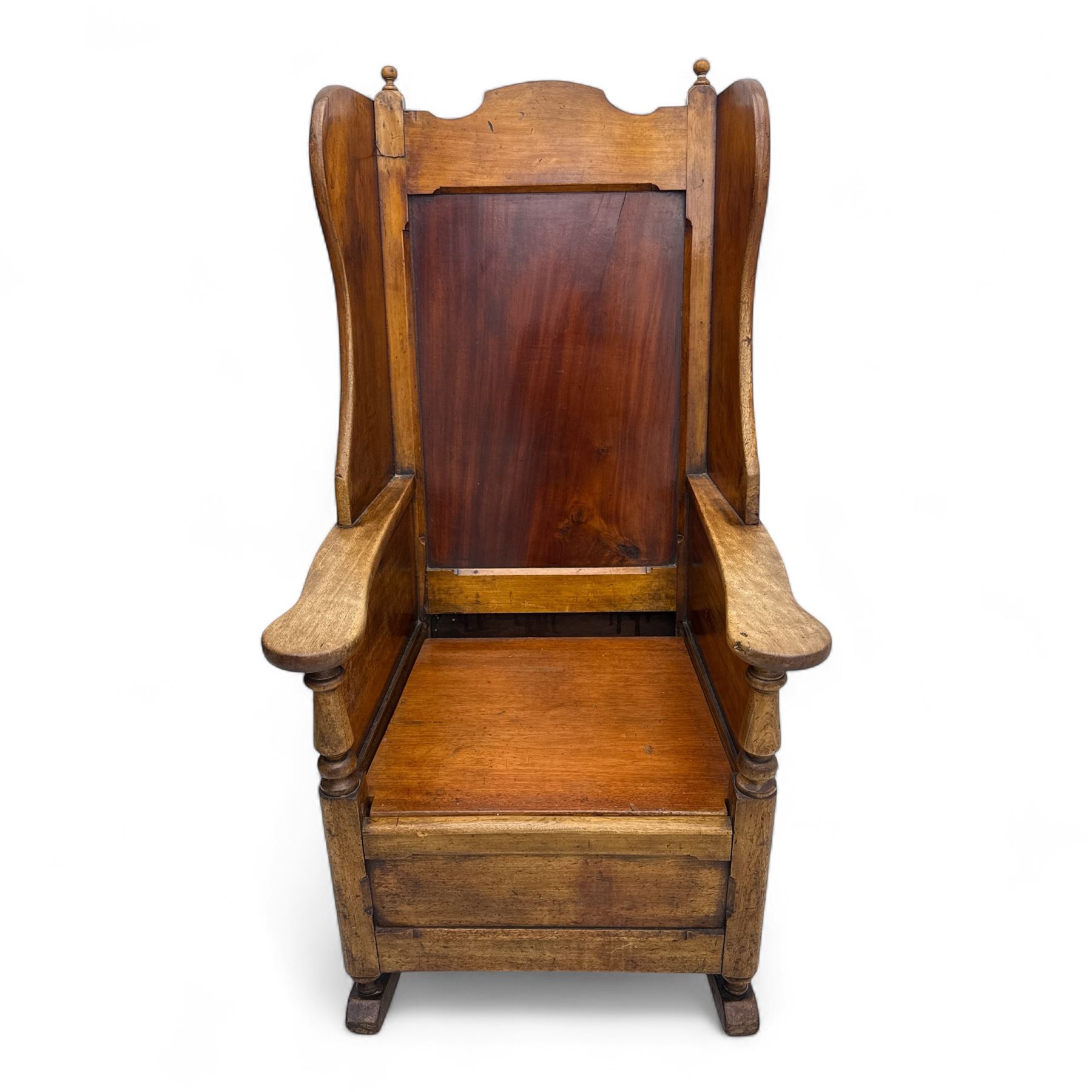 19th-century beech, yew, elm, and mahogany wingback vernacular rocking chair, high back with shaped wings, scroll arms with turned supports, lift-up seat,  square legs on ring turned supports on curved runners 