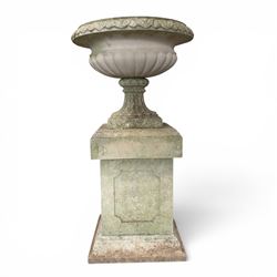 Pair of weathered cast stone Neoclassical design garden Kylix shape urns, foliate moulded rim over a gadrooned underbelly, the scalloped socle over a rectangular pedestal with faux-panelled sides, stamped with stylised ‘H’ monogram