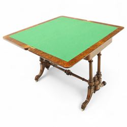 Victorian walnut and inlaid games table, rectangular fold-over top with figured walnut veneers and foliate inlay, swivel and fold over to reveal a green baize lined playing surface, on twin supports united by a stretcher, raised on scroll carved feet with castors (extended 96cm x 92cm)