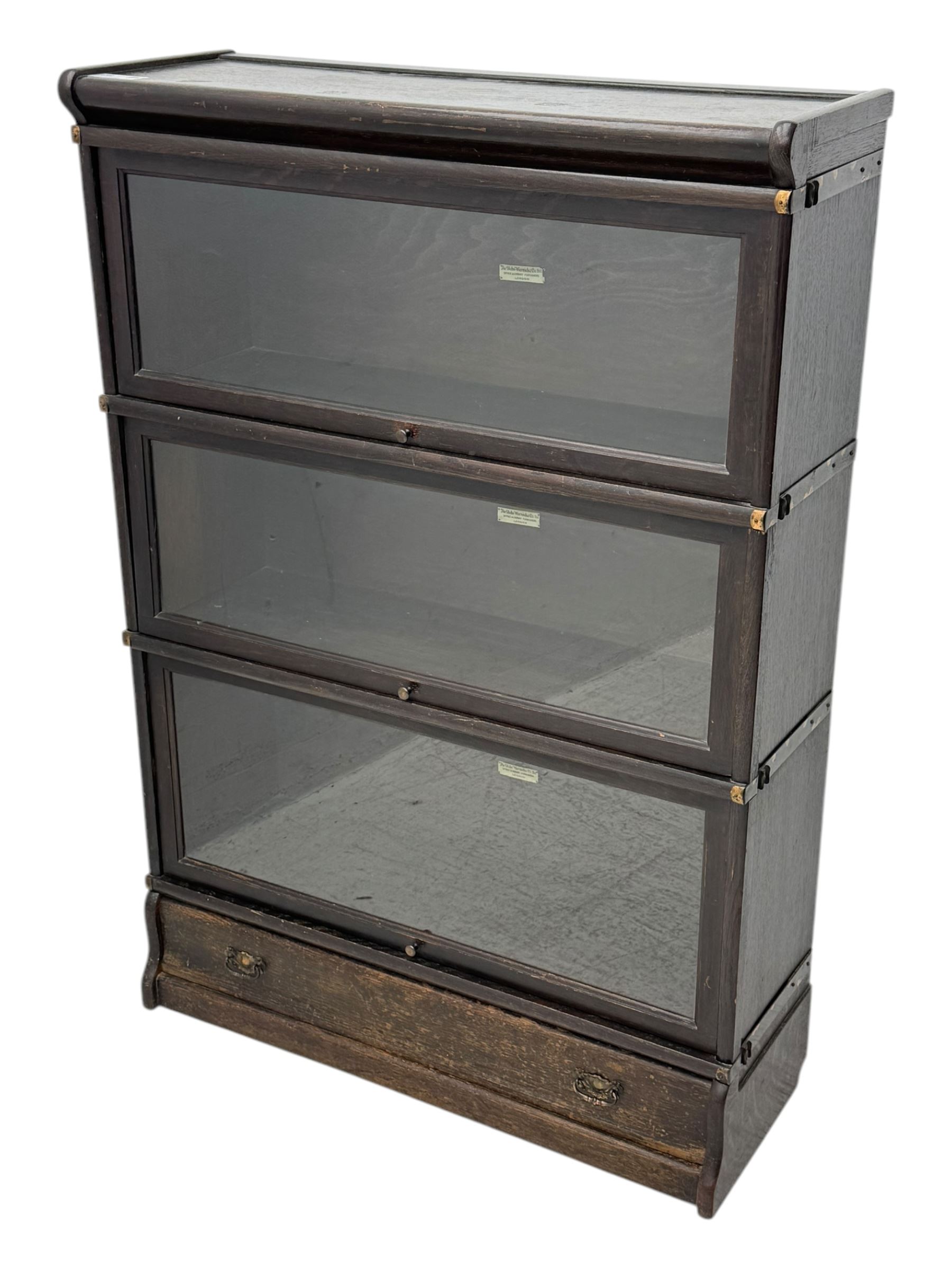 Globe Wernicke - early 20th century oak three-tier stacking library bookcase, three glazed sections enclosed by hinged and sliding doors, raised above a single lower drawer with metal drop handles