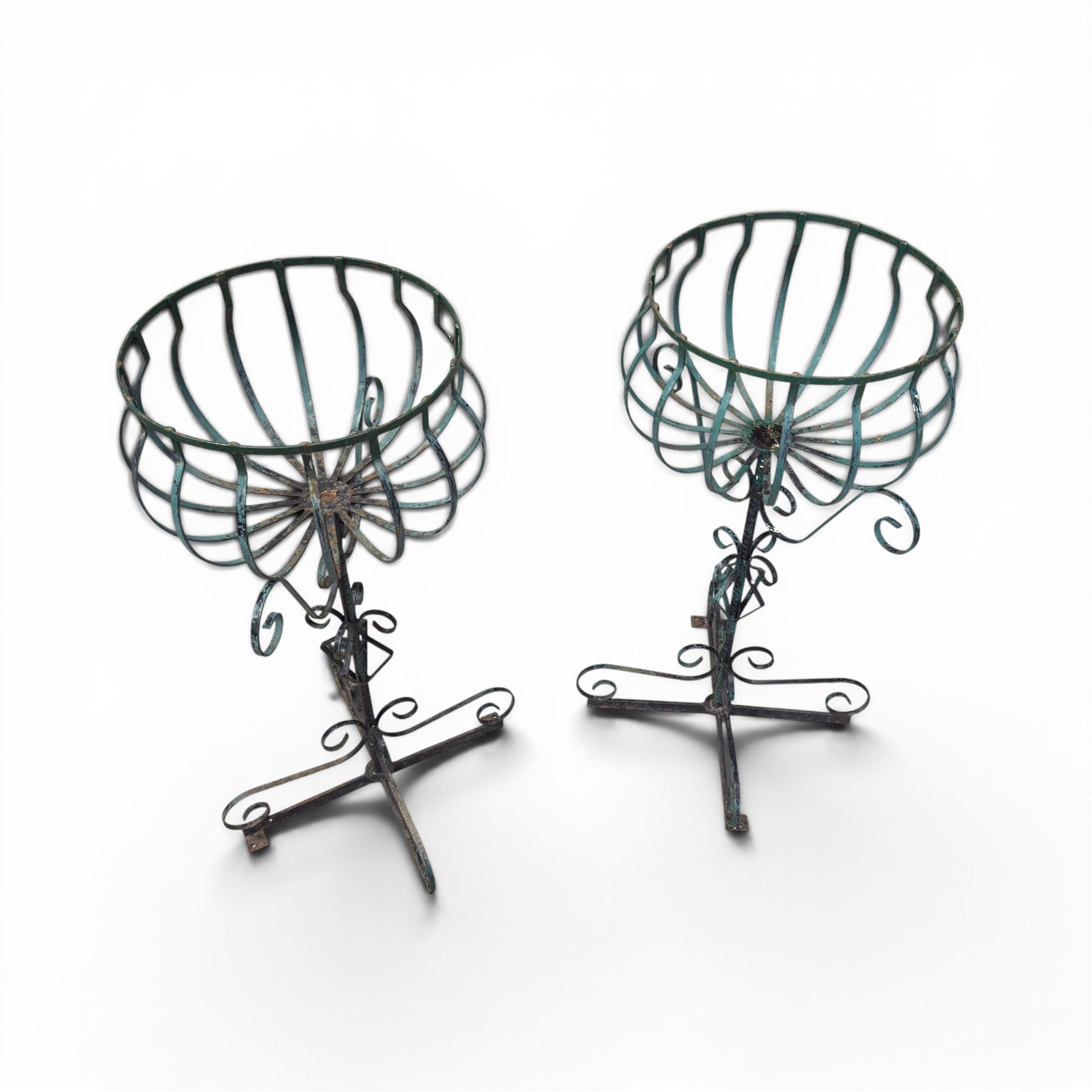 Matched pair of antique metal plant stands, each with circular strapwork basket tops, the scrollwork supports raised on an X-form base, in green painted finish with rustic patina